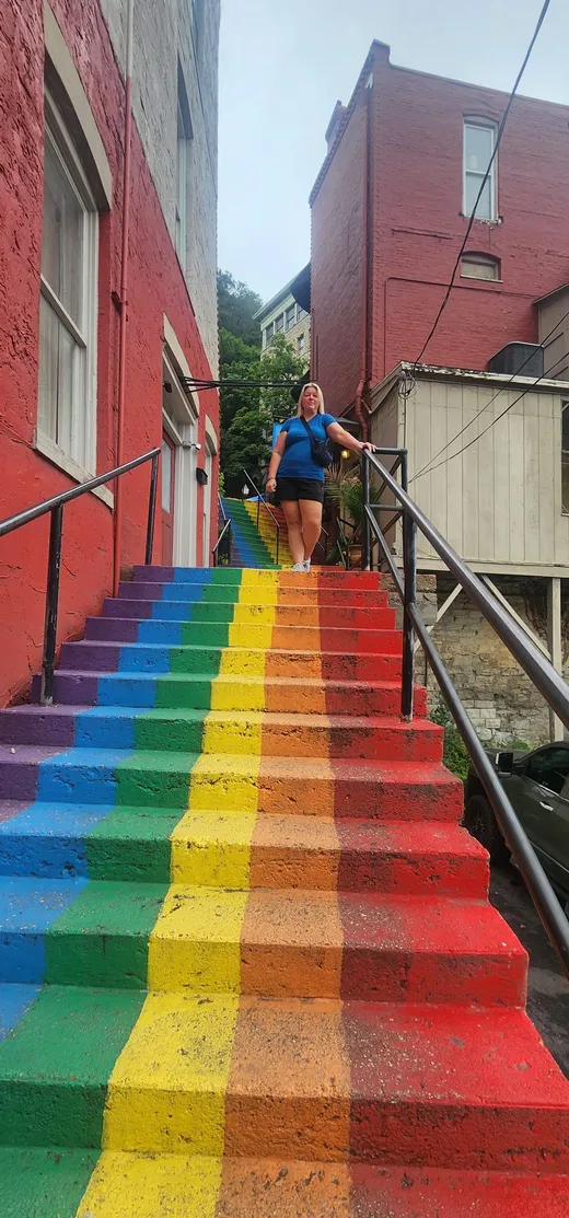 Brittany standing at the top of colorful rainbow-painted stairs