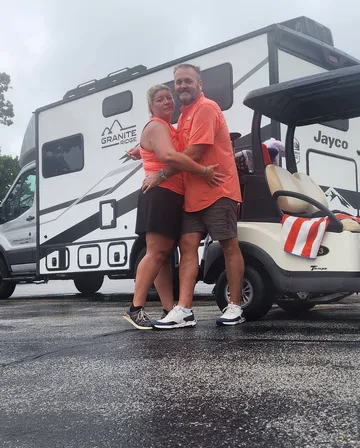 Kenny and Brittany hugging in front of their RV and golf cart